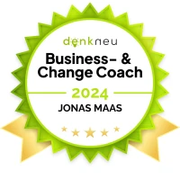Ein grünes Abzeichen mit goldenen Akzenten, das den Titel "Business- & Change Coach 2024" trägt und den Namen "JONAS MAAS" zeigt.